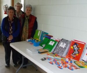 Three women pose with school supplies.