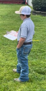 A kid holds a clipboard on a lawn.